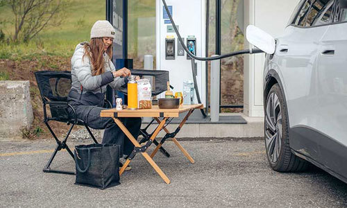 Kvinna äter frukost vid en laddstation